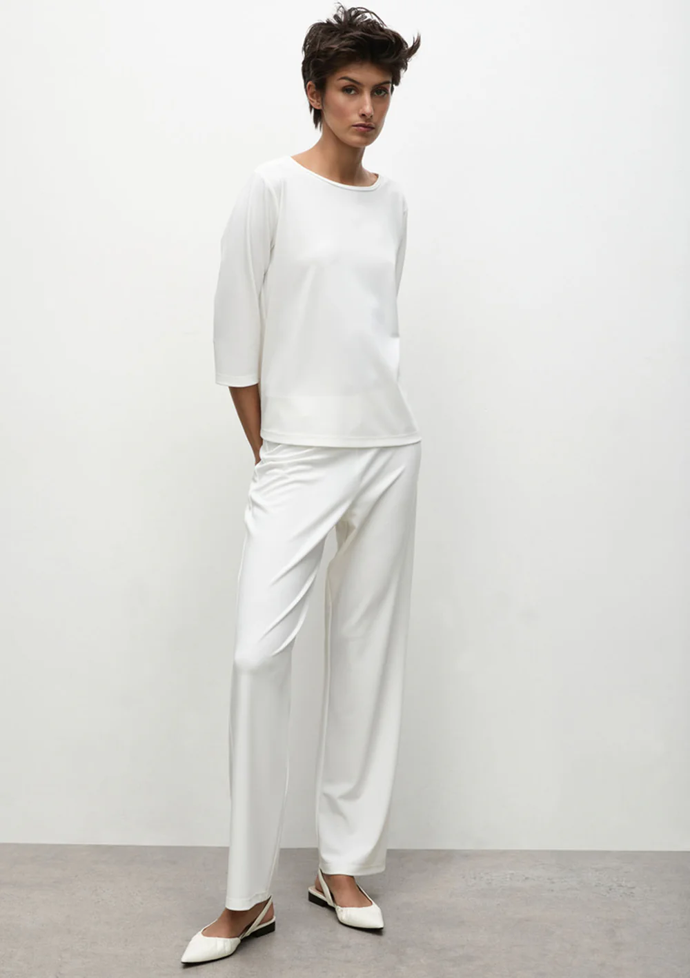 Person wearing a white outfit with a plain background