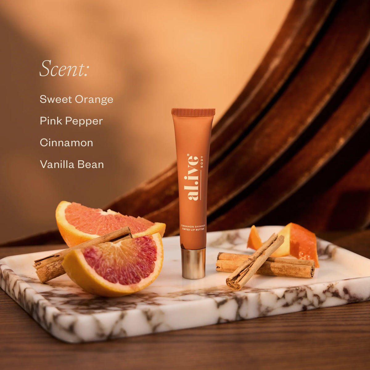 al.ive body Cinnamon Shimmer Tinted Lip Butter with blood orange and cinnamon on marble