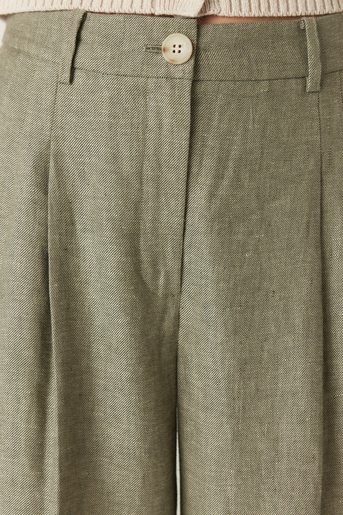 Close-up of the button fly and waistband detail on the Cable Melbourne Evelyn Linen Pant in Green