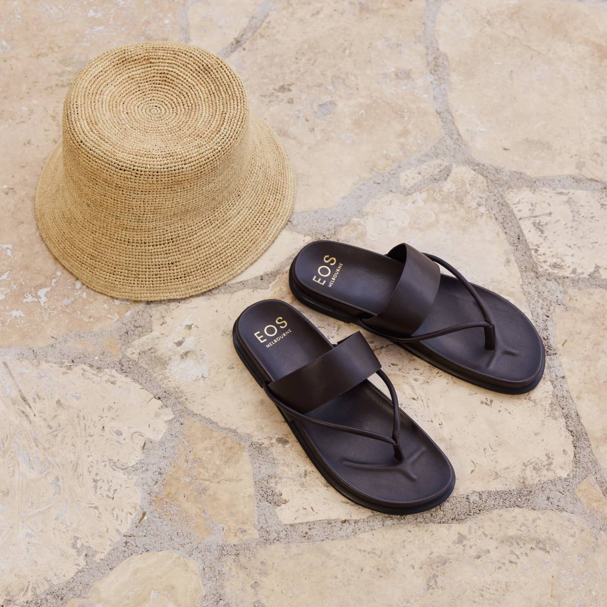 EOS Nalea leather thong slides in Chestnut styled with a straw bucket hat on stone