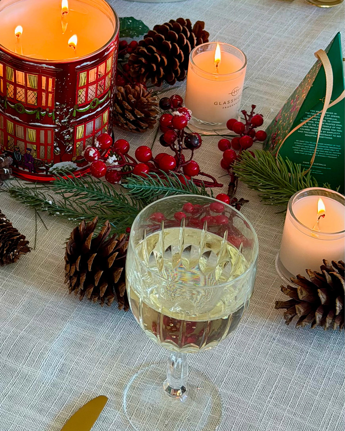 Glasshouse Fragrances Night Before Christmas Candles in 60g and 380g on a Christmas table with pine cones